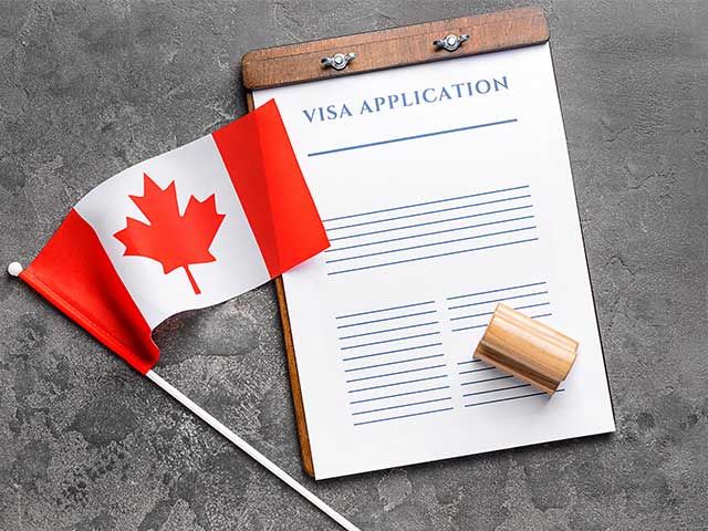 Visa application form, stamp and Canadian flag on table